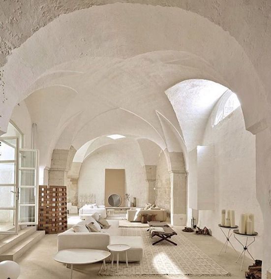 the interior of a large white room with arched ceilings and stone walls, along with modern furniture