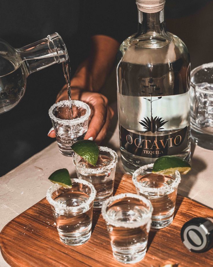 a person pouring water into glasses on top of a wooden tray with mints and ice cubes