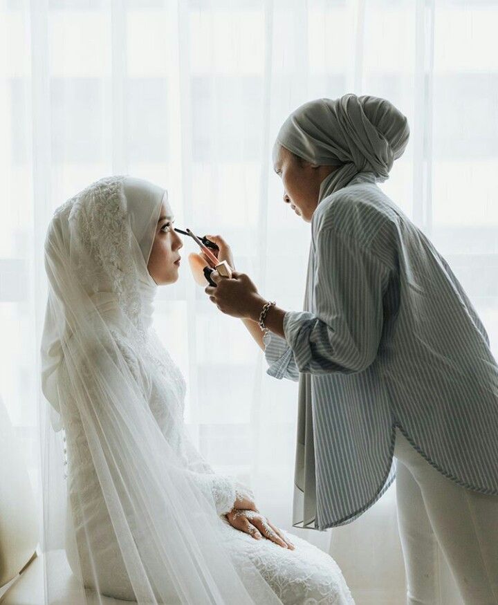 two women dressed in white are getting ready for their wedding