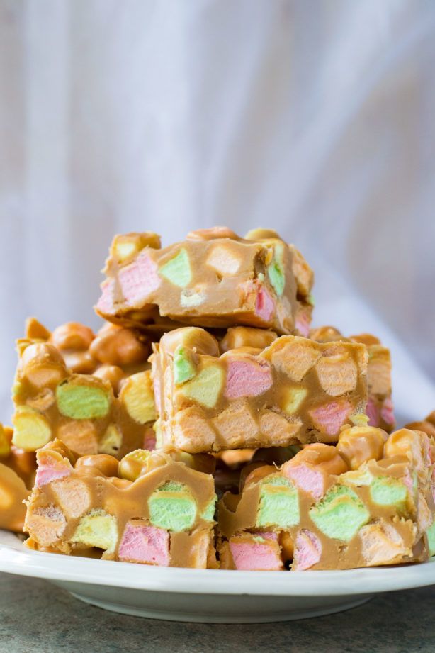 a white plate topped with marshmallows and pretzel squares covered in candy