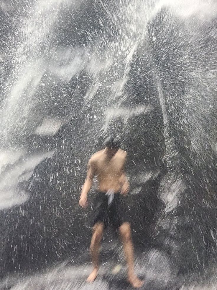 a man running in the rain with an umbrella over his head and water splashing on him