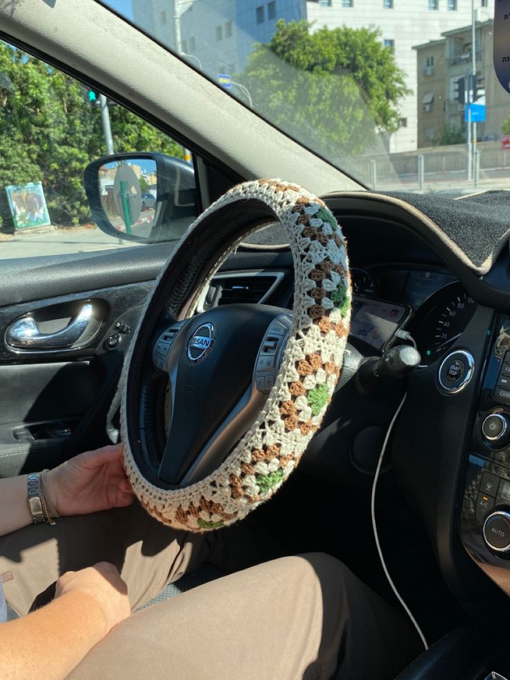 a woman is sitting in the driver's seat of a car with her hand on the steering wheel