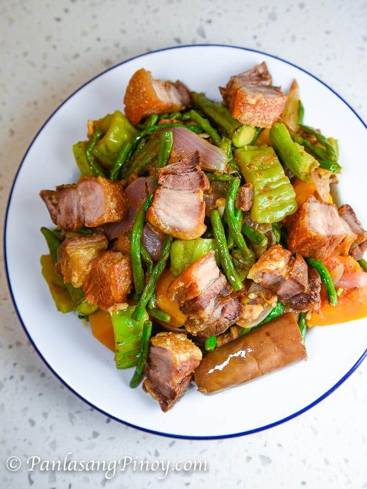 a white plate topped with meat and veggies on top of a marble counter