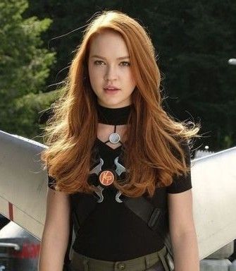 a woman with long red hair is standing in front of an airplane and holding a surfboard