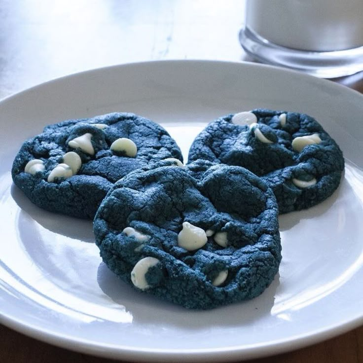 three blue cookies are on a white plate