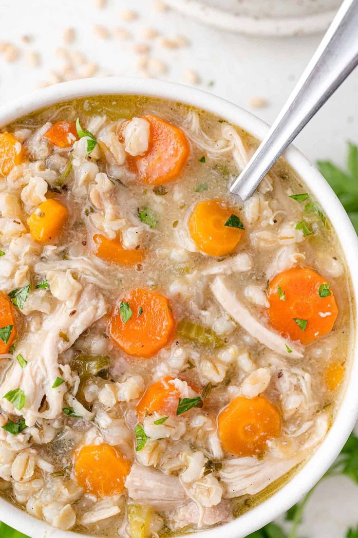 a bowl of chicken and rice soup with carrots, celery and parsley