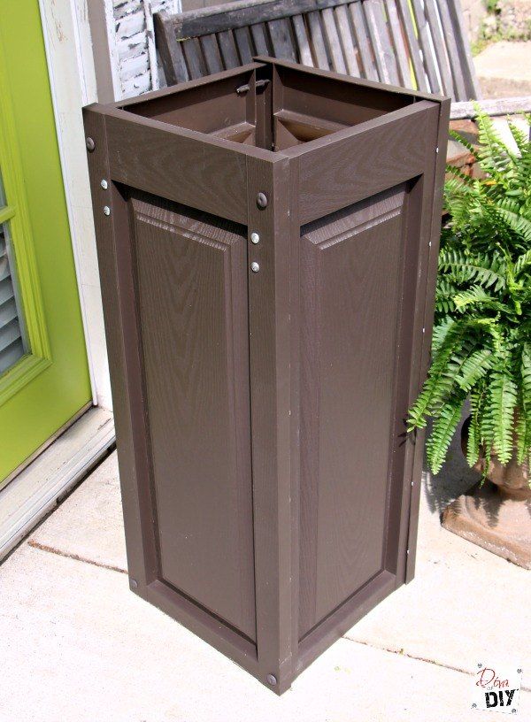 a brown trash can sitting next to a green door