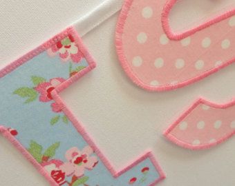 the letters are made out of fabric and decorated with pink flowers, polka dots and green leaves