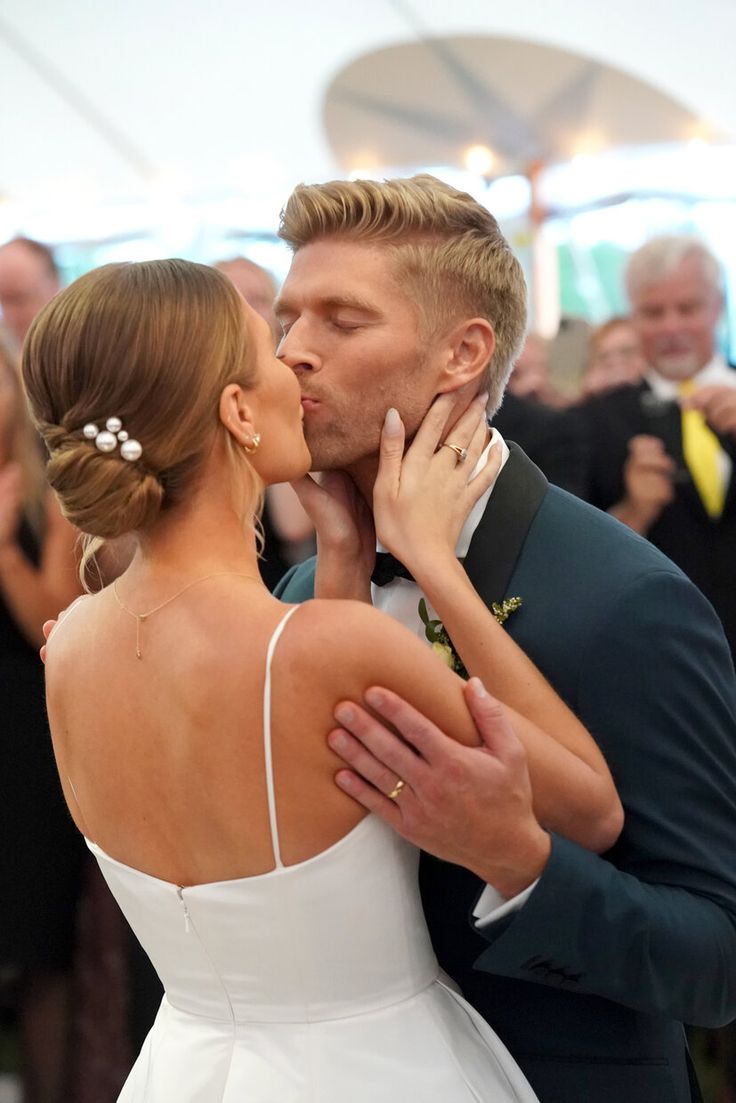 a bride and groom kissing on the dance floor at their wedding reception with guests in the background