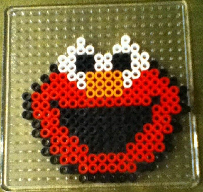 a red and black beaded object on a metal tray with white dots around it