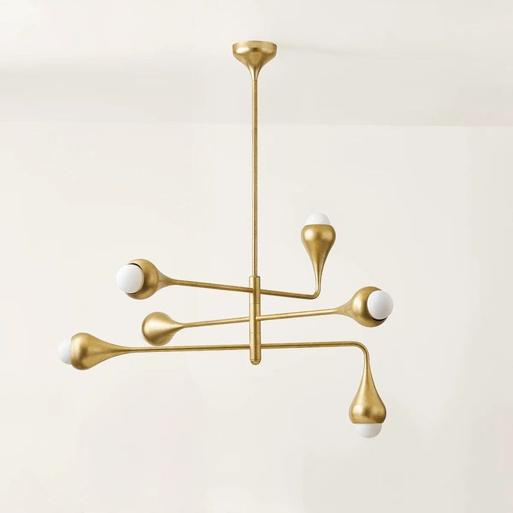 a gold chandelier with five white balls hanging from it's center point