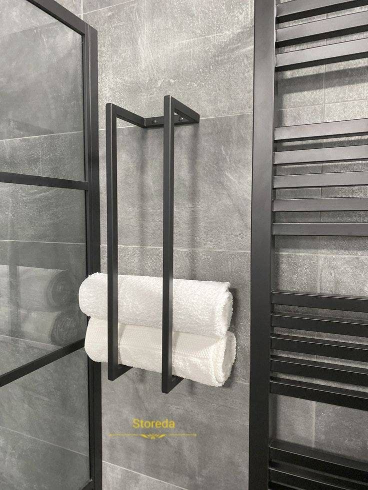 a black and white photo of a towel rack in a bathroom