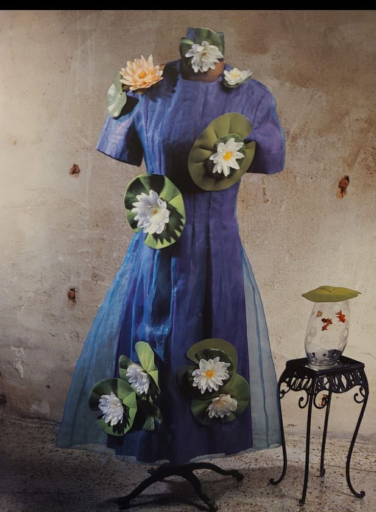 a dress made out of paper flowers sitting on top of a table