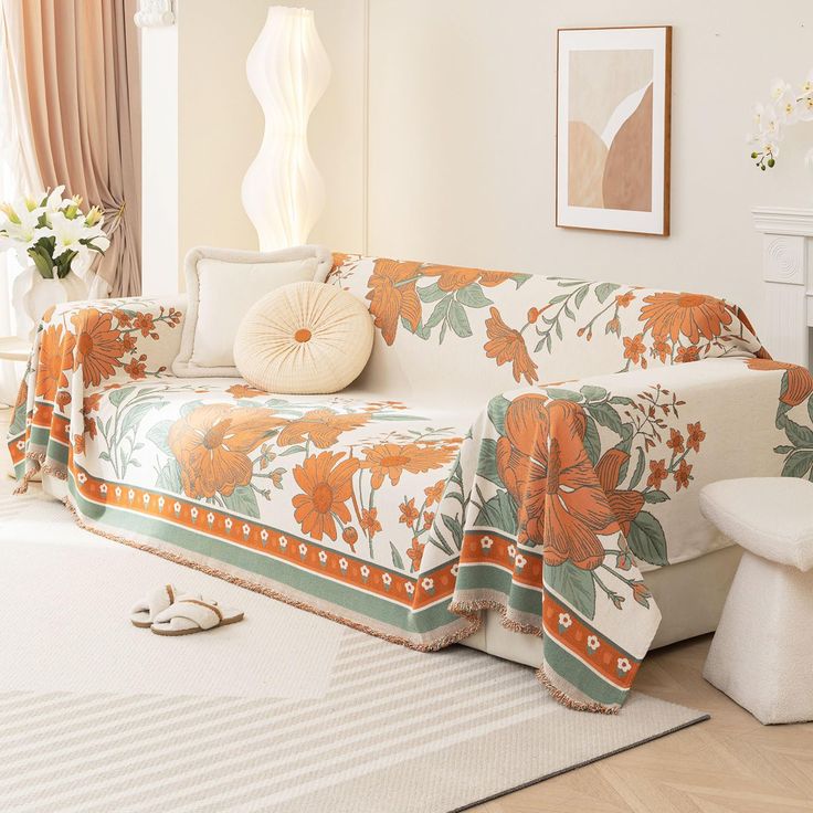 a living room with white furniture and orange flowers on the couches, rugs and pillows