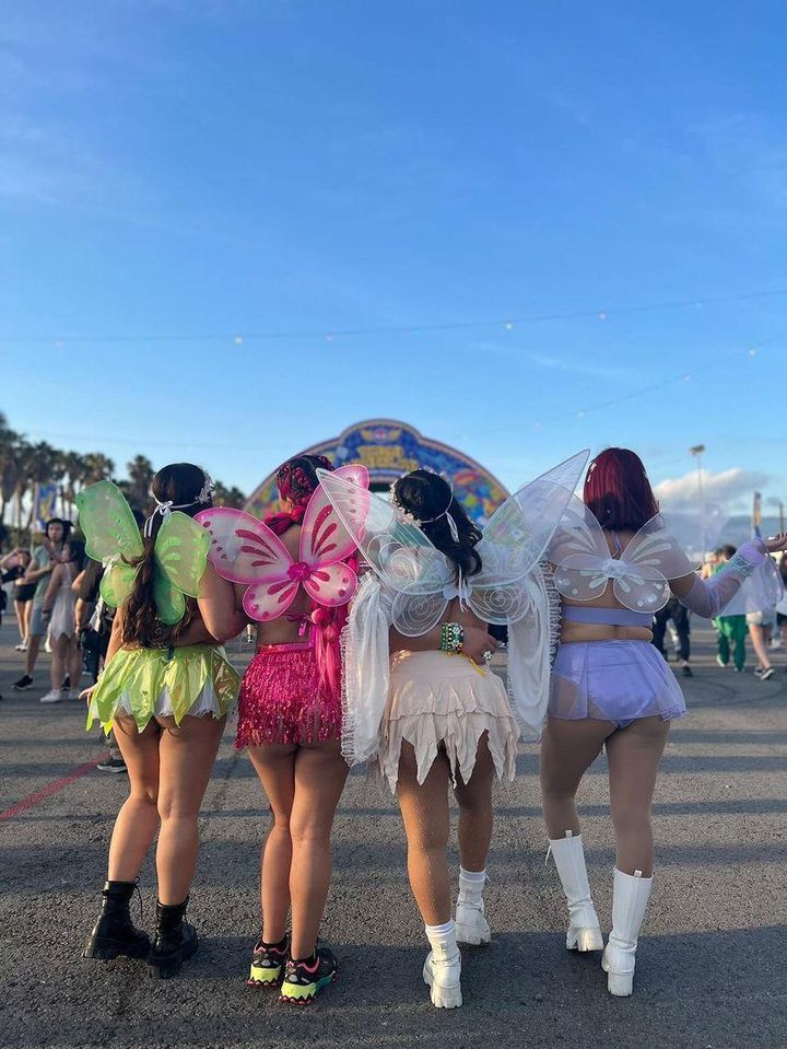 three women dressed in fairy costumes walk down the street with their backs to each other