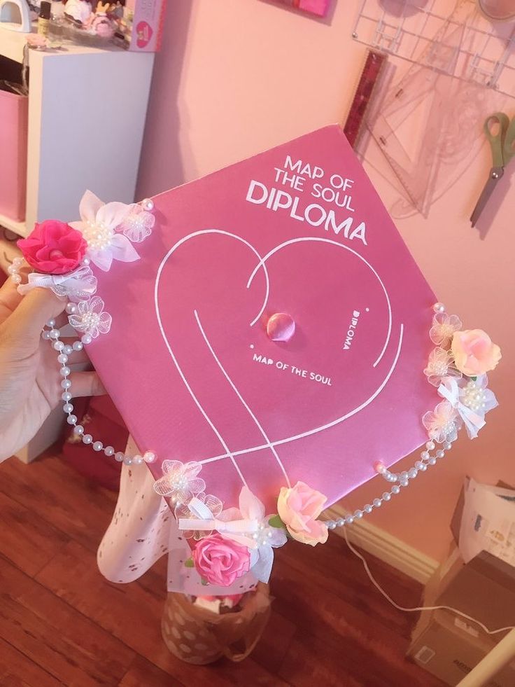 a pink graduation cap that says made in the shape of a heart with flowers on it