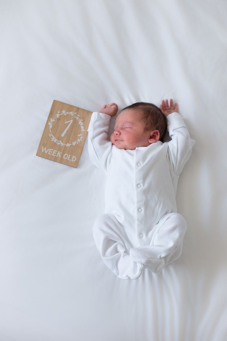 a baby is sleeping on a white bed with a wooden sign that says ween's old