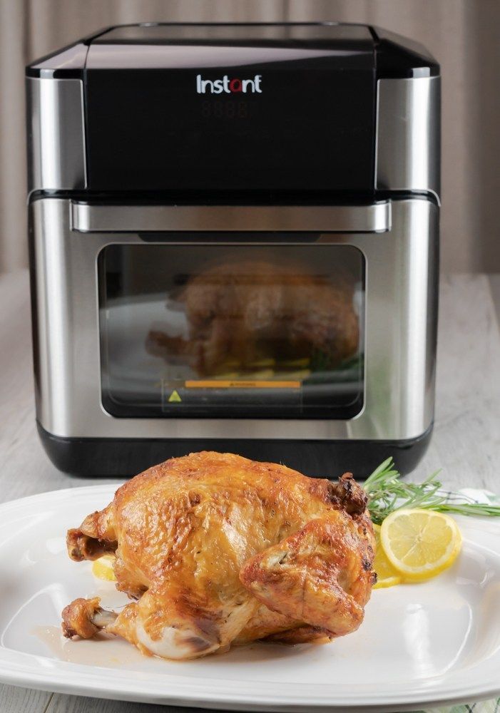 a cooked chicken sitting on a plate in front of an instant pot roaster oven