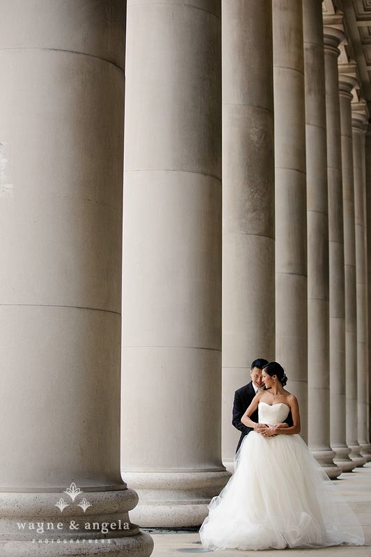 a bride and groom standing in front of columns