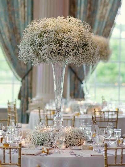 an elegant centerpiece with baby's breath flowers is displayed on a round table