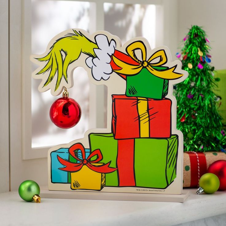 a christmas card with the grin on top of it and presents in front of a window