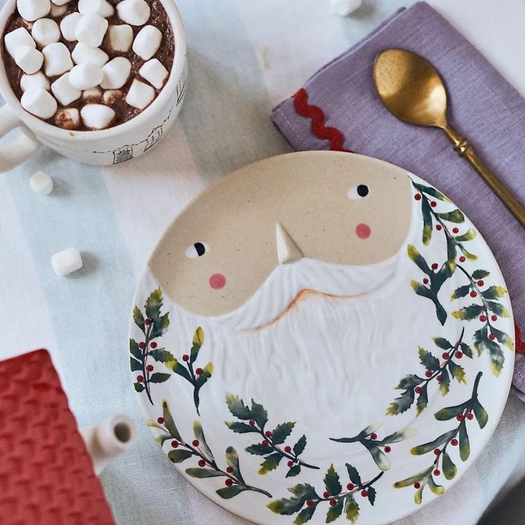 a santa clause plate sitting on top of a table next to a cup of coffee