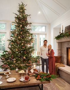 a man and woman standing in front of a christmas tree