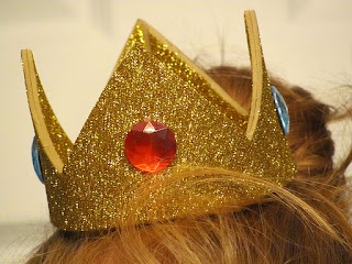 a close up of a person wearing a gold crown with a red jewel on it