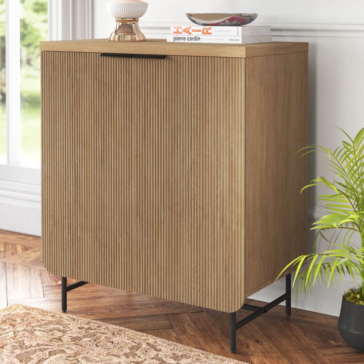 a wooden cabinet sitting on top of a hard wood floor next to a potted plant