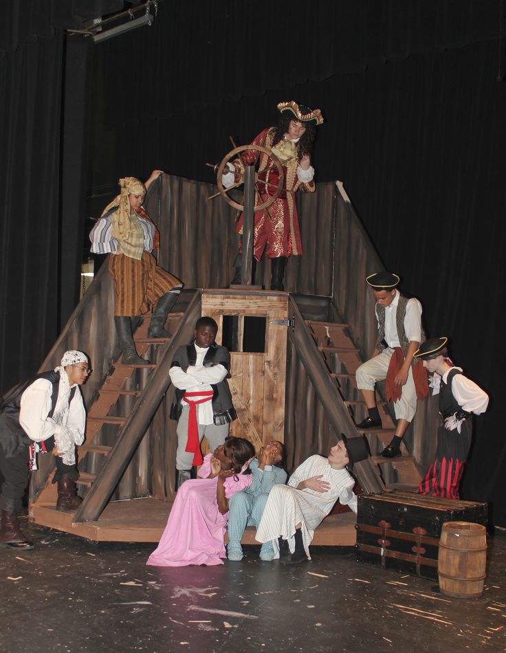 children dressed up in costumes on stage with adults and children standing around the stage playing