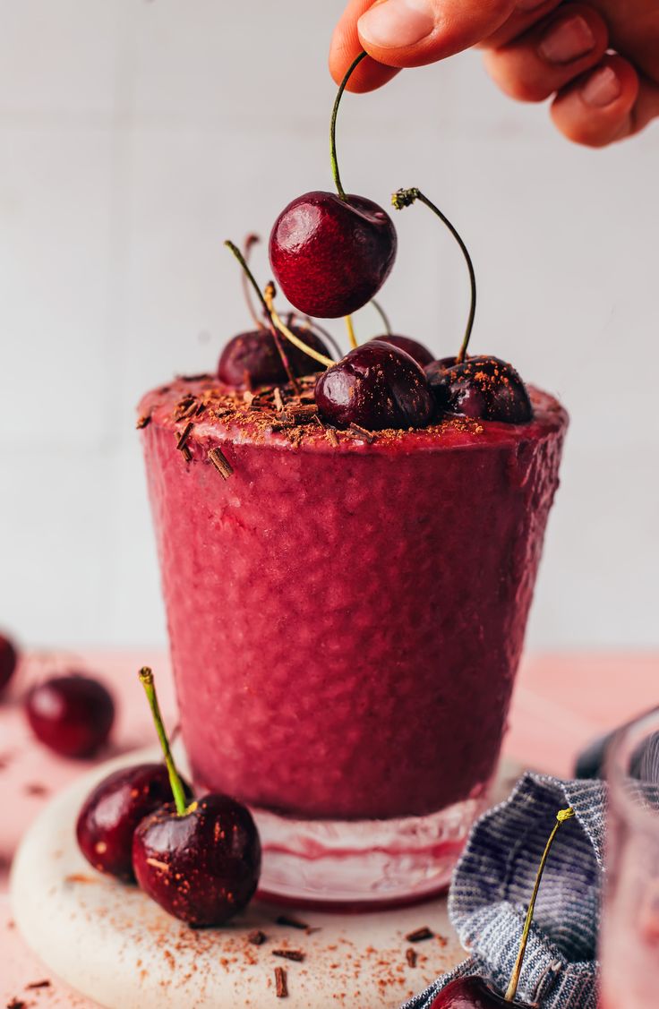 a person is picking up cherries from a smoothie