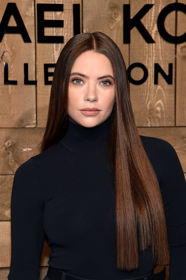 a woman with long brown hair standing in front of a wooden sign that says kalei kohle ellen