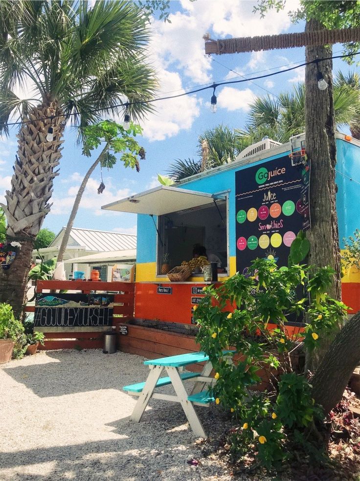 an ice cream truck parked in front of a palm tree and blue sky with clouds