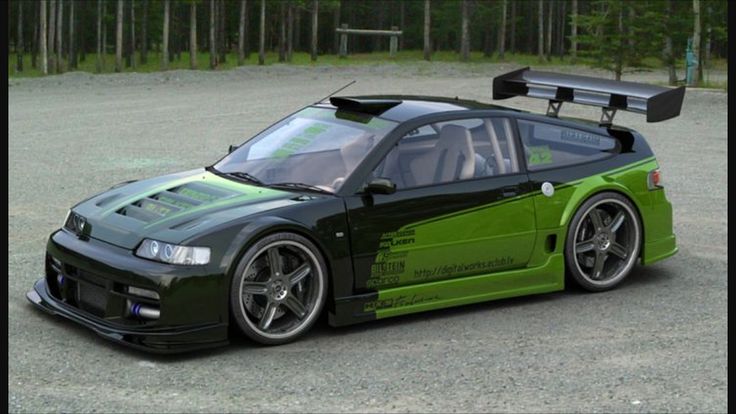 a green sports car parked in a parking lot with trees in the backgroud