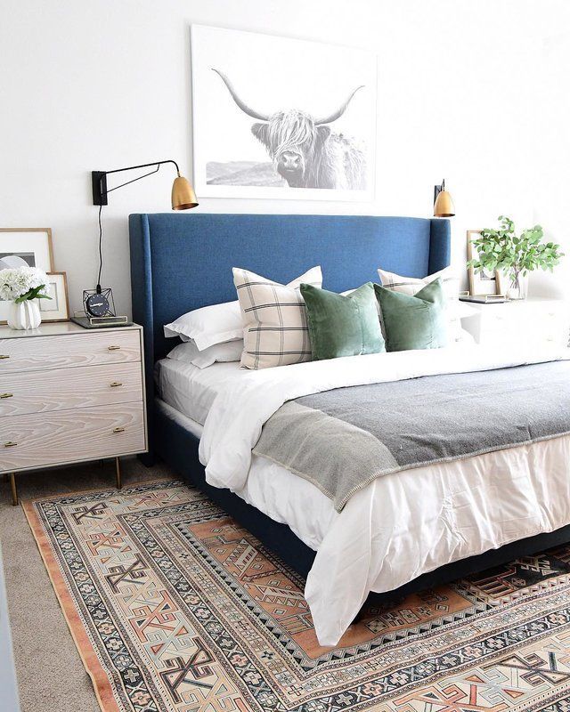 a bedroom with a blue headboard and rugs on the floor next to it