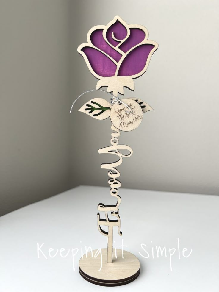 a purple and white flower on top of a wooden stand with the words happy birthday written in cursive writing