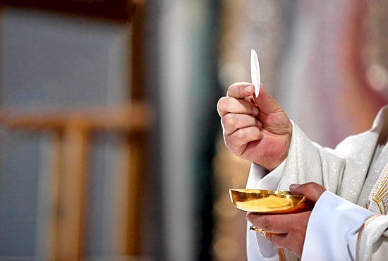 the priest is holding a small bowl with something in it's hand and pointing at it