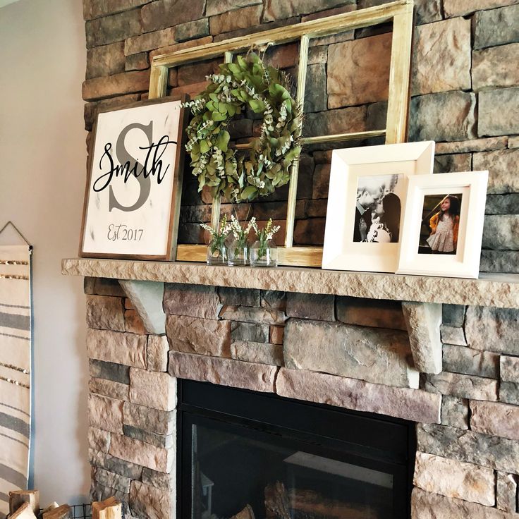 a mantle with pictures and wreaths on it in front of a fireplace mantel