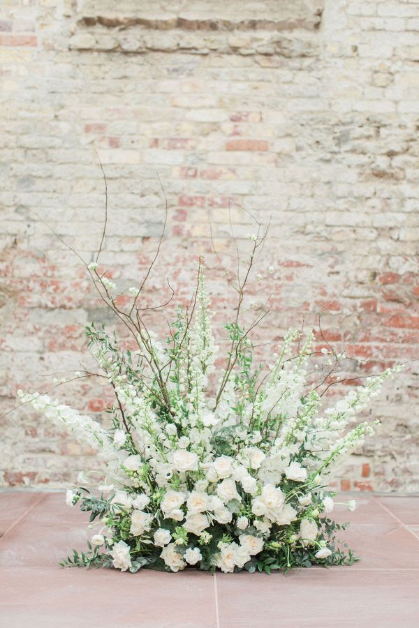 a bouquet of white flowers sitting on top of a table next to a brick wall