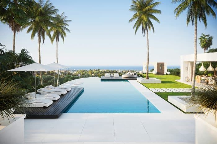 an outdoor swimming pool with lounge chairs and umbrellas next to the water, surrounded by palm trees