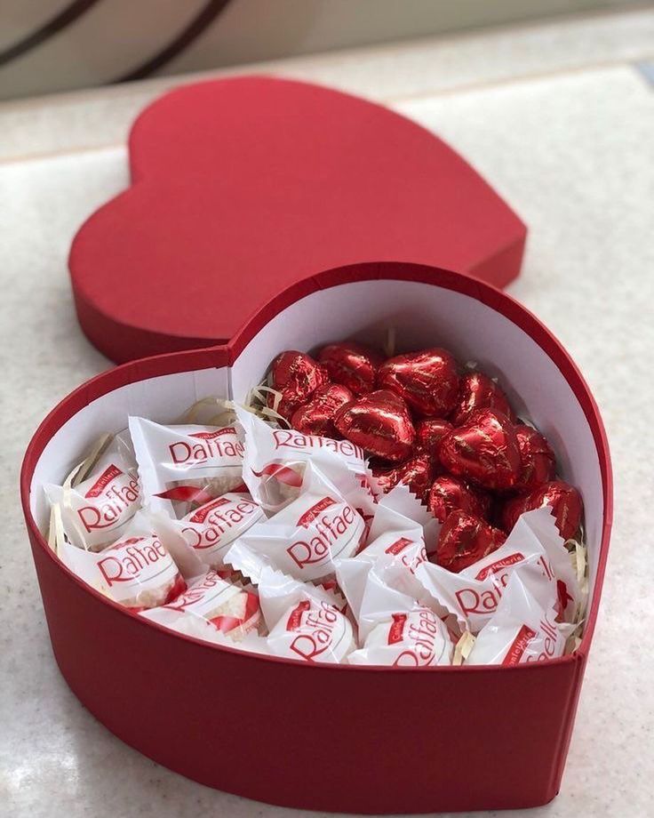 a heart shaped box filled with chocolates on top of a white counter next to a red box