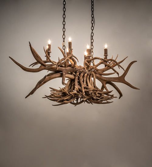 a chandelier made out of antlers hanging from chains with candles in them