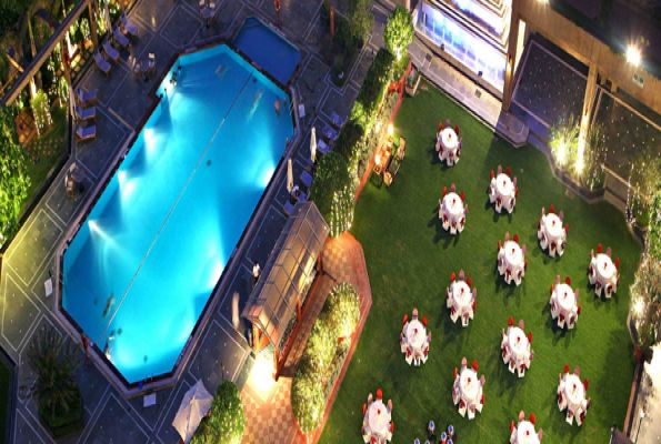 an aerial view of a lawn with tables and chairs next to a swimming pool at night