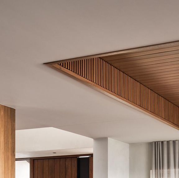 a living room filled with furniture next to a wooden wall and window covered in sheer curtains