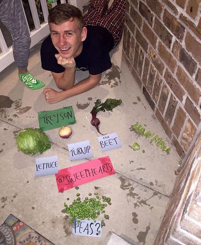 a young man laying on the floor with vegetables and words written on them in front of him