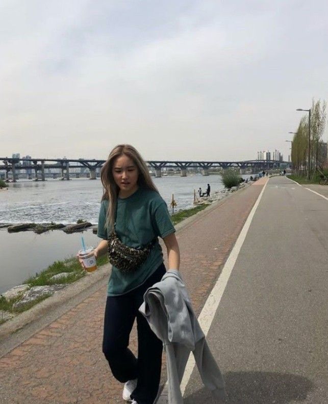 a woman is walking down the street with her hand in her pocket and holding something