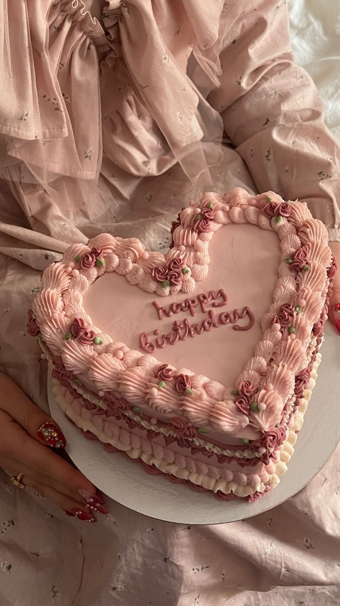 a heart shaped cake sitting on top of a table next to a woman's hand