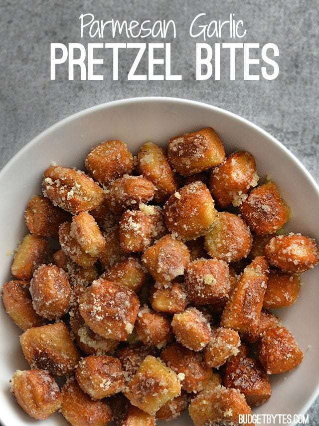 a white bowl filled with parmesan garlic pretzel bites on top of a table