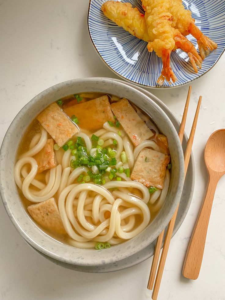 there is noodle soup in the bowl on the table with chopsticks next to it