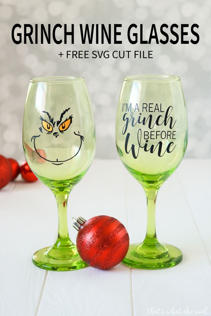 two wine glasses sitting next to each other on top of a white table with red ornaments